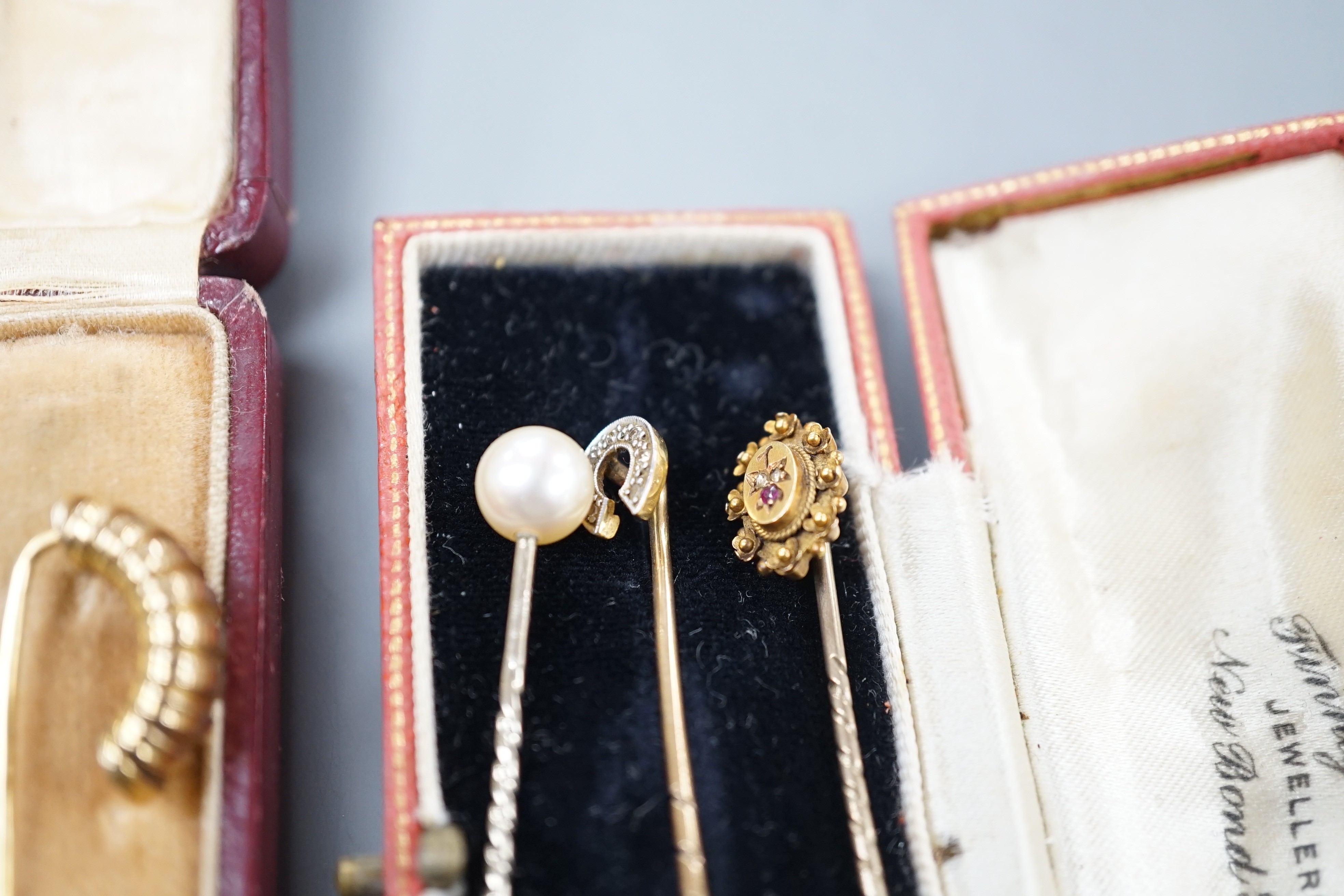Three assorted early to mid 20th century yellow metal and gem set stick pins including diamond chip set horseshoe, 57mm and 15ct ruby and diamond chip and two other stick pins.